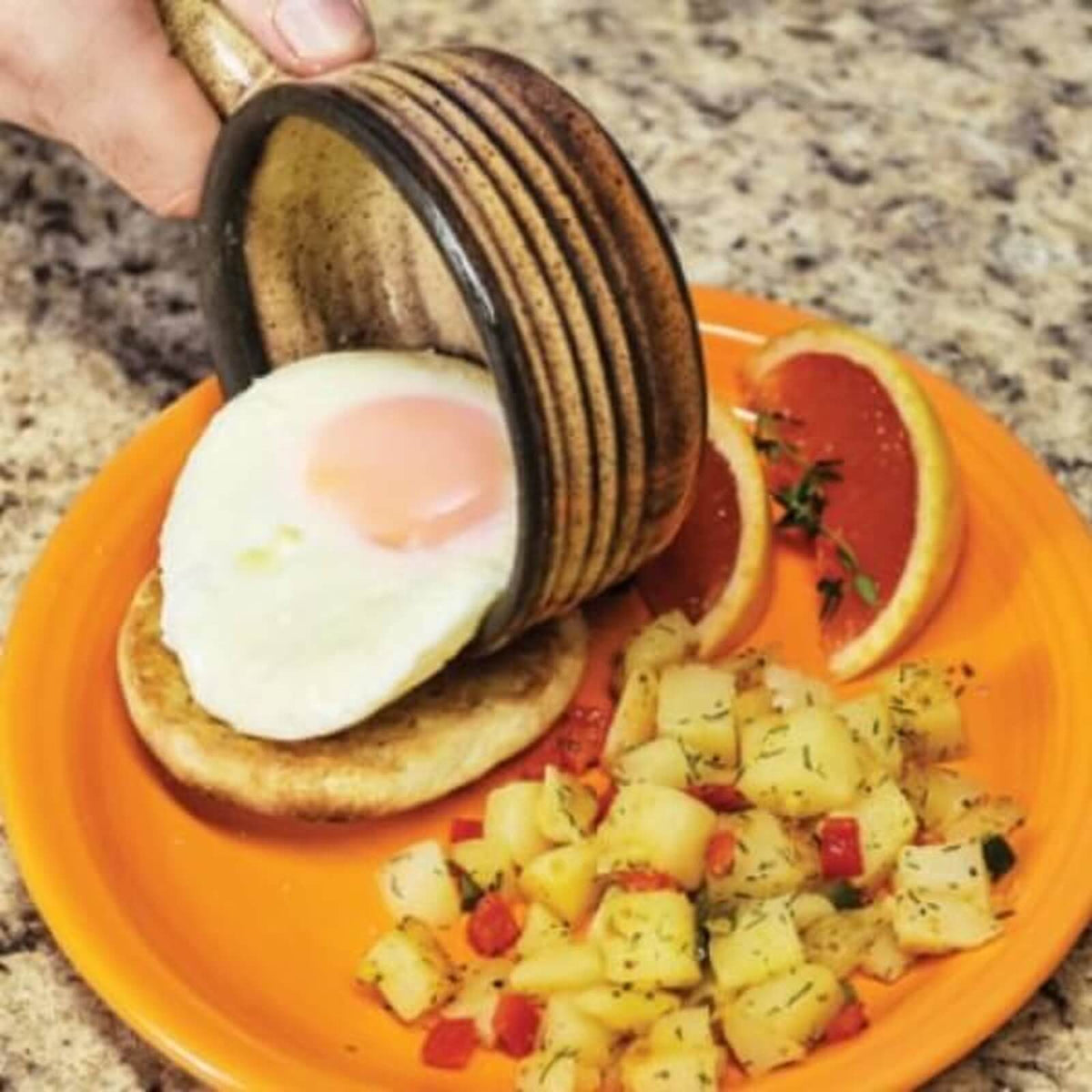 Cooked egg served from a ceramic microwave cooker with breakfast potatoes
