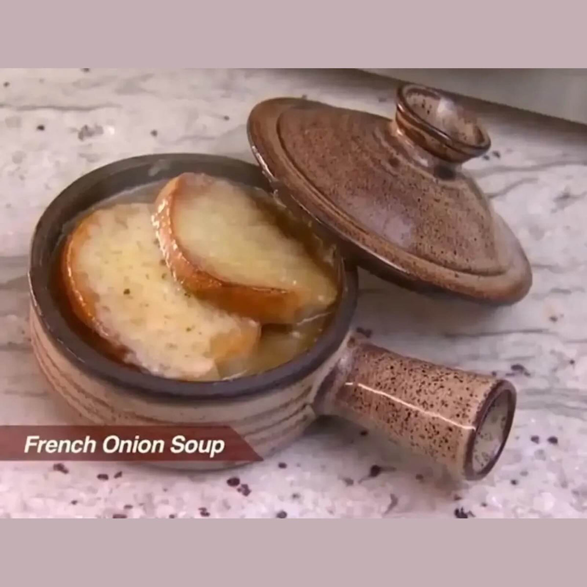 Finished French onion soup with melted cheese in a ceramic microwave cooker