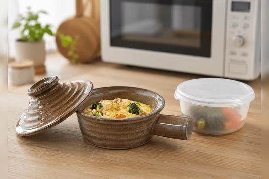 Ceramic microwave cooker beside a plastic microwave container on a kitchen counter.