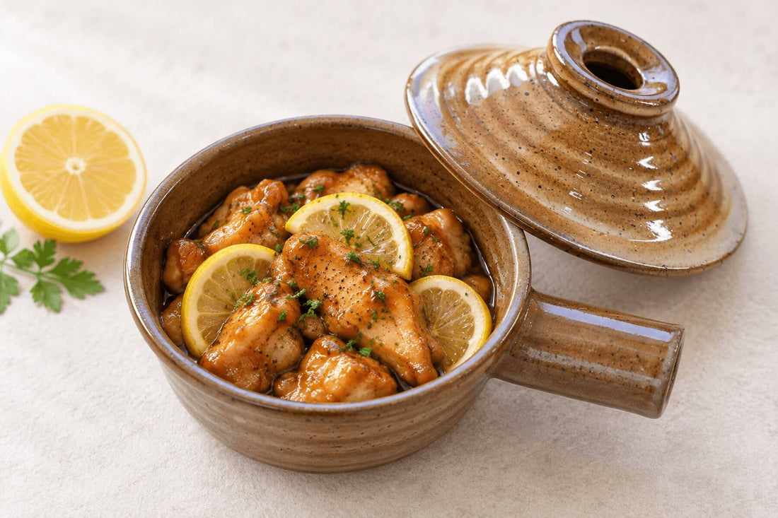Honey lemon chicken in a ceramic microwave cooker with lemon slices and herbs.