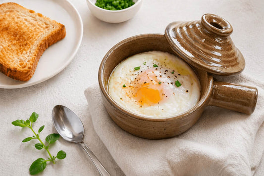 Poached egg in a ceramic microwave cooker with toast on the side.