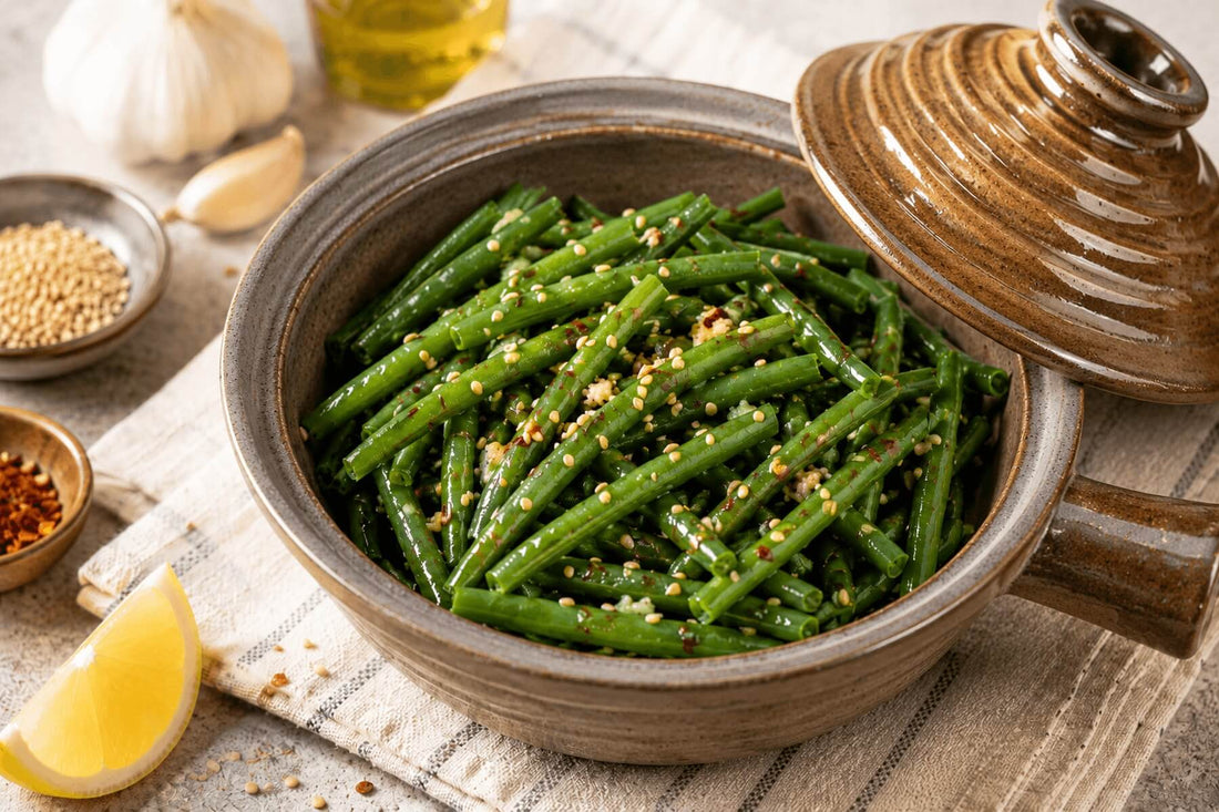 Spicy sesame green beans in a ceramic microwave cooker with sesame seeds and lemon.