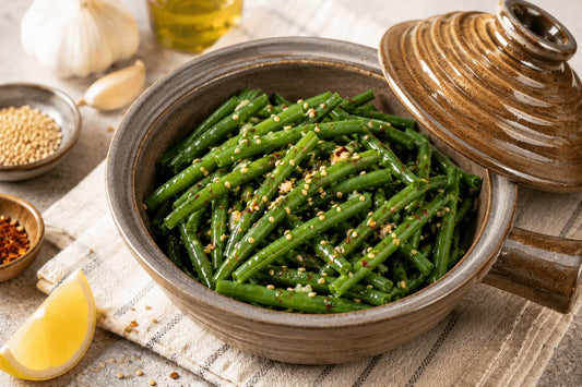 Spicy sesame green beans in a ceramic microwave cooker with sesame seeds and lemon.