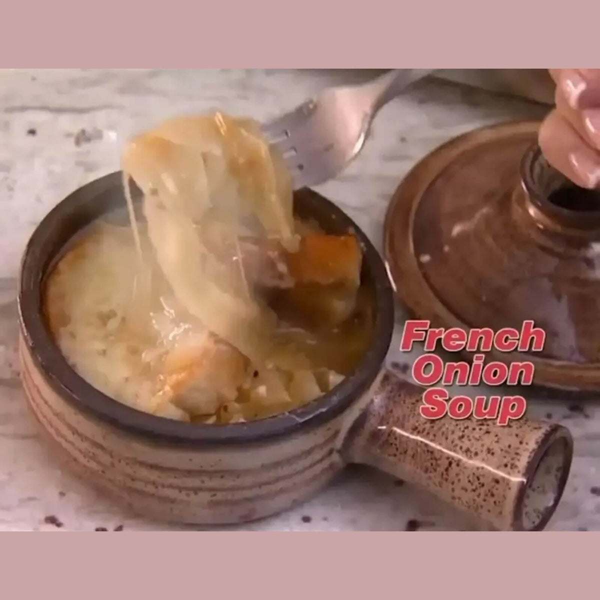 French onion soup with melted cheese being lifted from a ceramic microwave cooker