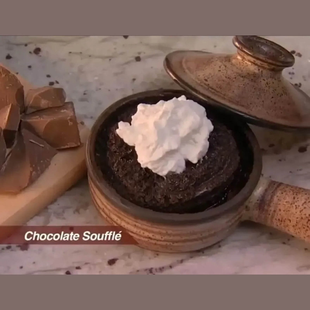 Chocolate souffle topped with whipped cream in a ceramic microwave cooker